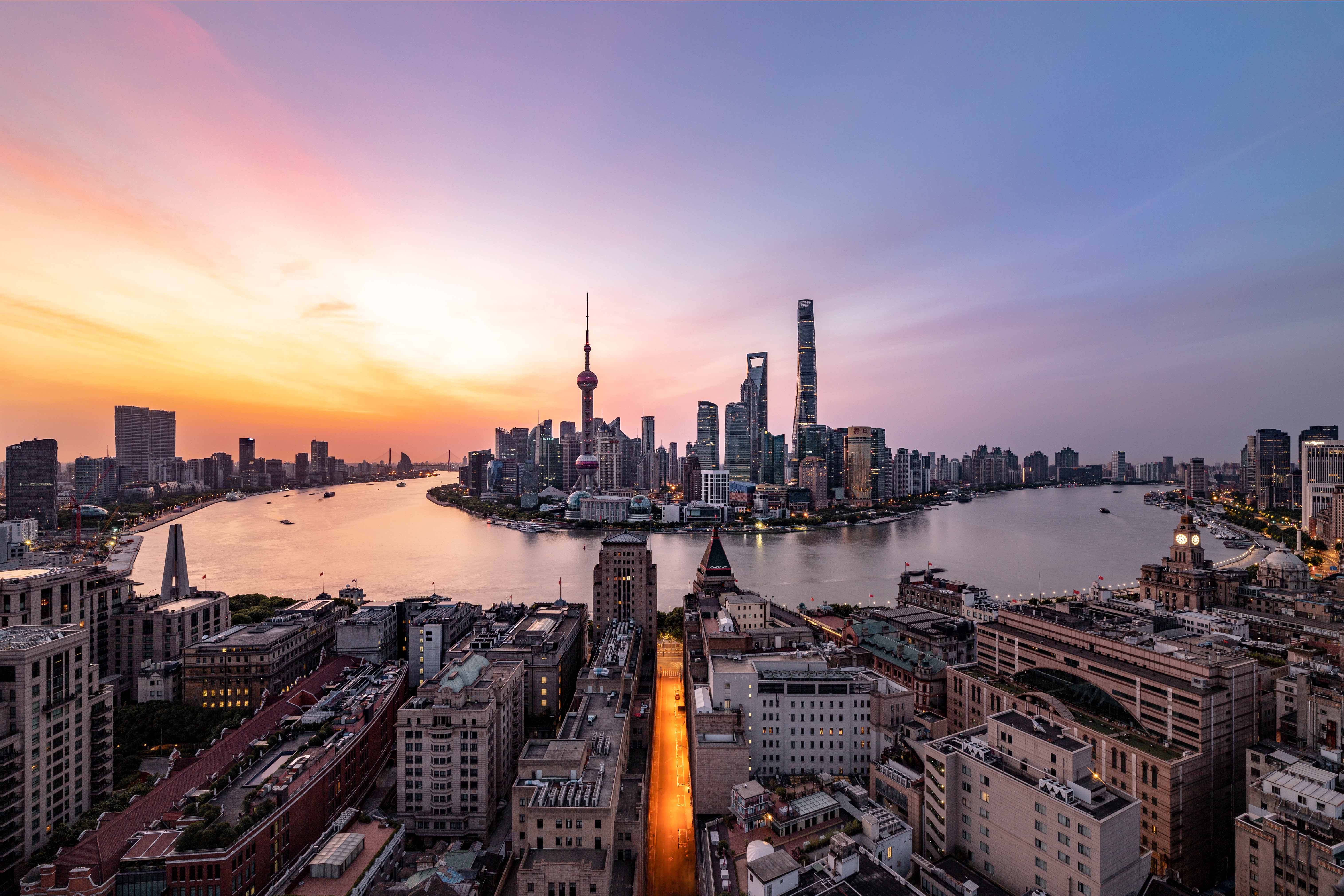 现代办公大楼外景，玻璃幕墙反射阳光，周围绿植环绕，体现专业企业形象